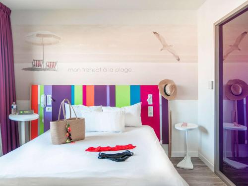 莱萨布勒-多洛讷ibis Styles Les Sables Olonne的一间卧室配有一张带色彩缤纷床头板的床
