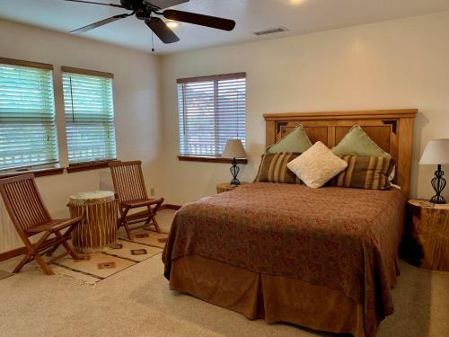 埃斯卡兰特Slot Canyons Inn Bed & Breakfast的一间卧室配有一张带两把椅子的床和吊扇
