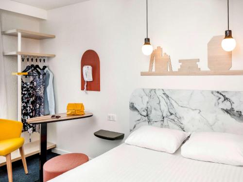 维希Hôtel ibis Styles Vichy Centre的一间卧室配有一张床、一张桌子和一张桌子