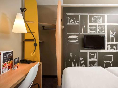 布鲁塞尔布鲁塞尔伊拉斯谟斯宜必思酒店的一间卧室配有一张床,墙上配有电视
