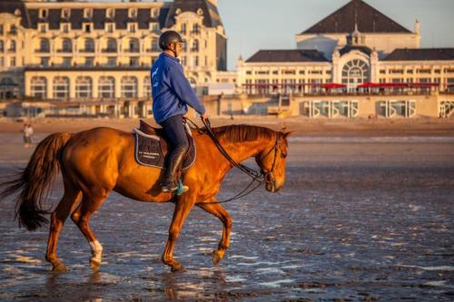 卡布尔Home sweet home Cabourg plage的骑马在海滩上的人