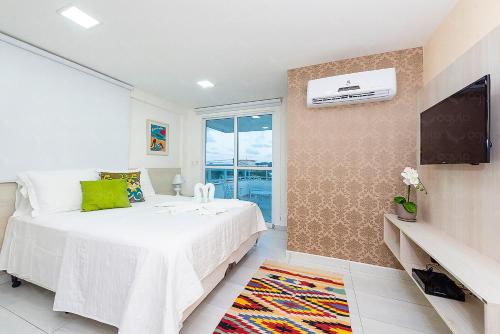 纳塔尔Águia Flats Pousada的卧室配有白色的床和电视