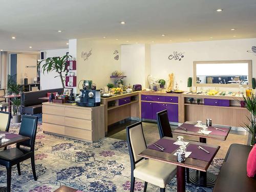 瑟松塞维涅雷恩塞松美居酒店的一间带桌子的餐厅以及一间带紫色橱柜的厨房