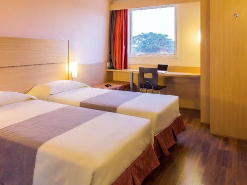 莫索罗Ibis Mossoro的酒店客房配有两张床和一张书桌