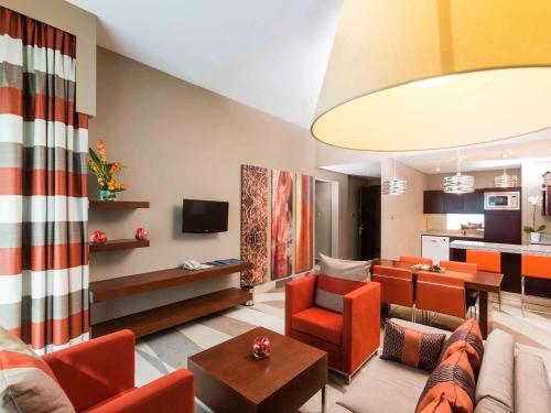 迪拜迪拜阿尔巴沙诺富特酒店的一间带橙色家具的客厅和厨房