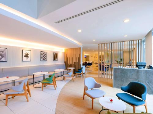 曼谷宜必思曼谷沙吞酒店 的一间设有桌椅的等候室和一间酒吧