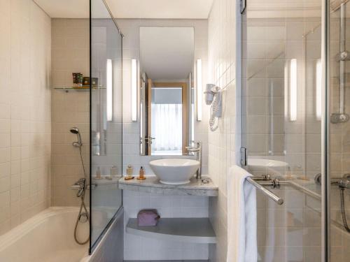 迪拜Novotel Suites Mall Avenue Dubai的一间带水槽和玻璃淋浴的浴室