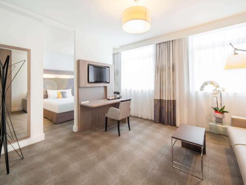 雷恩诺富特SPA雷恩中心火车站酒店的酒店客房配有床、桌子和沙发。