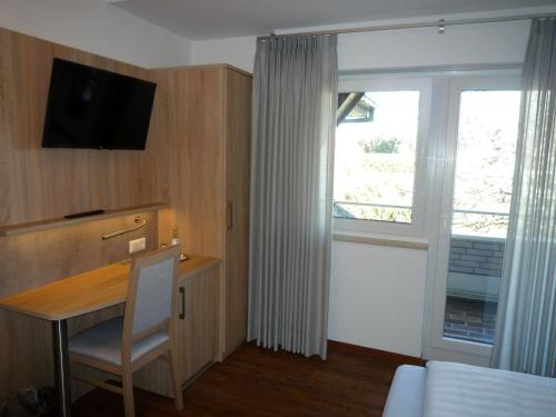 林根Hotel - Restaurant Veldscholten的客房设有书桌、电视和窗户。