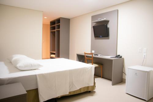 大坎普Orla Morena Park Hotel的一间卧室配有一张床、一张书桌和一台电视。
