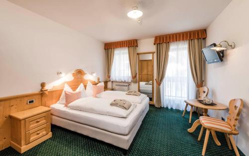 拉维拉Garni La Ciasota 3s的酒店客房设有一张大床和一张桌子。