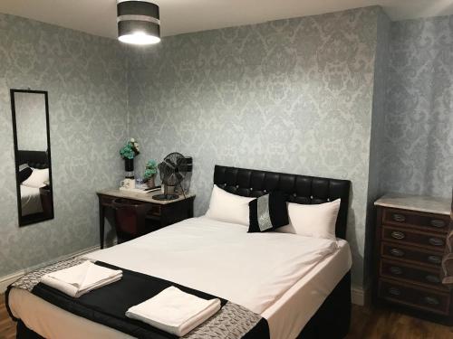 绍斯霍伦敦希思罗机场太平洋酒店 的一间卧室配有一张带梳妆台和镜子的床
