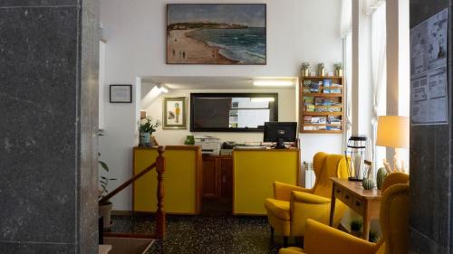 柯米拉斯Hotel Josein的一间设有黄色椅子和书桌的等候室