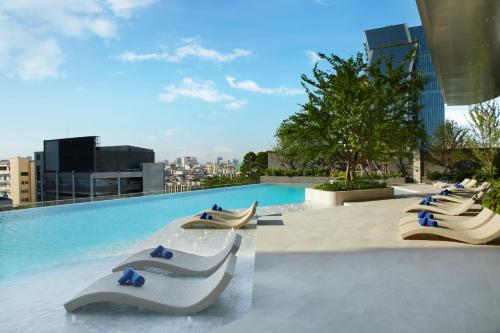 曼谷曼谷盛捷拉玛9服务公寓的一座带躺椅的游泳池位于一座建筑的顶部