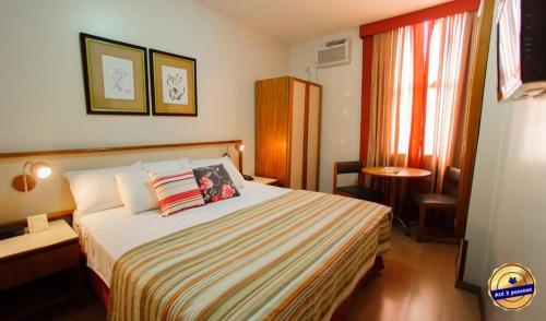 尤西德福拉César Inn Juiz de Fora Hotel的酒店客房设有床、桌子和窗户。