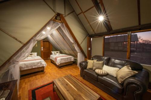 曼耶雷蒂野生动物园Buffelshoek Tented Camp的一间带真皮沙发的客厅和一间卧室
