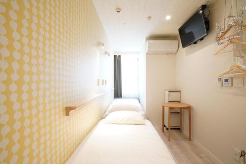 东京U-Hotel Takadanobaba的一间设有三张床的客房,墙上设有一台电视