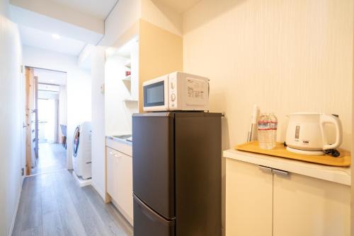 东京ZAITO Tokyo Kinshicho Economy Inn 宅东东京横川1民宿的厨房配有冰箱上方的微波炉