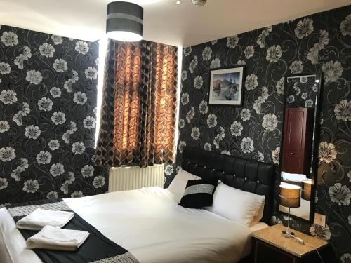 绍斯霍伦敦希思罗机场太平洋酒店 的一间卧室配有一张床和一张带花卉壁纸的墙壁