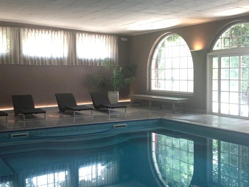罗阿纳Hotel Vecchia Stazione Mountain Elegance的一个带椅子和桌子的游泳池以及窗户