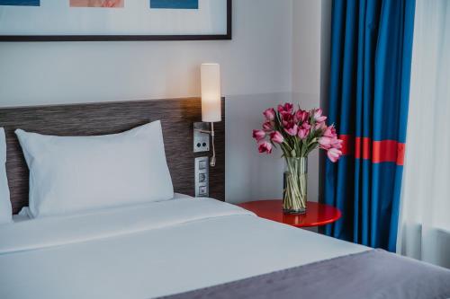 彼得罗扎沃茨克皮特尔酒店的一间卧室,配有一张床,桌子上放着花瓶