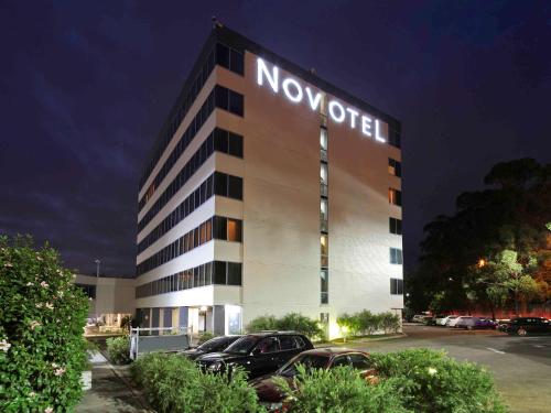 乐蒂山Novotel Sydney West HQ的创新酒店,停车场内有车辆停放