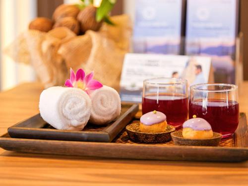 芭东海滩Grand Mercure Phuket Patong的托盘,带毛巾和两杯茶