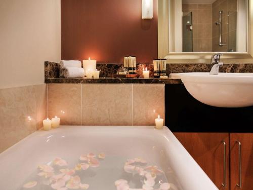 奥克兰奥克兰高架桥港塞贝尔酒店的浴室配有带蜡烛和水槽的浴缸。