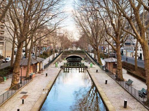 巴黎巴黎爱乐厅拉维莱特19号美居酒店的城市里一条有桥和树木的河流