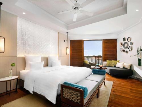 岘港岘港海滩铂尔曼度假酒店的卧室配有一张白色的大床和一张沙发。