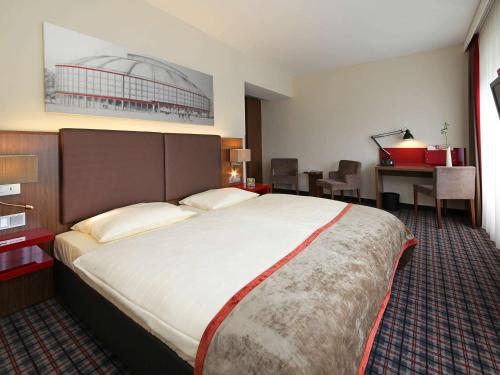 多特蒙德Mercure Hotel Dortmund Messe的酒店客房设有一张大床和一张书桌。