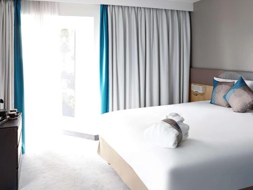 伦敦伦敦温布利诺富特酒店的卧室配有白色床和蓝色及白色枕头