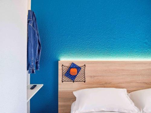 圣但尼hotelF1 Paris Saint Denis Stade的一间设有蓝色墙壁的卧室和一张带床头板的床