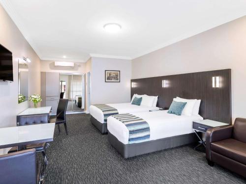 古尔本古尔本美居酒店的酒店客房配有两张床和一张书桌