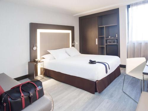 马德里马德里市中心诺富特酒店的酒店客房带一张大床和一把椅子