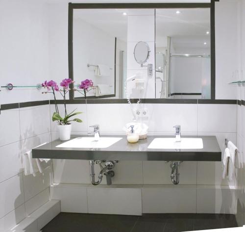 赖兴瑙Strandhotel Löchnerhaus的一间带两个盥洗盆和大镜子的浴室