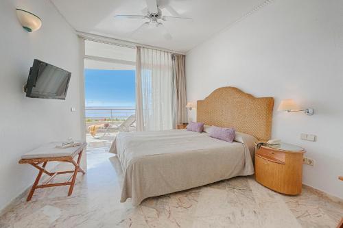 阿吉内金海滩Anfi del Mar 2的一间卧室设有一张床、一台电视和一个窗口。