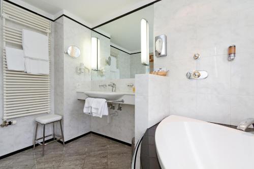 马洛亚施瓦泽豪斯瑞士优质酒店的白色的浴室设有水槽和镜子