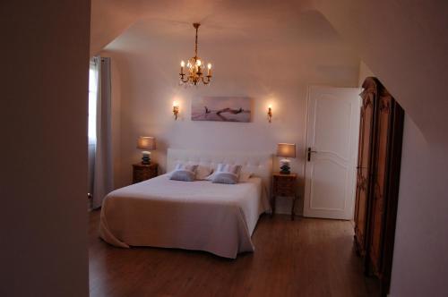 圣茹昂代盖雷特La Villa des Longchamps Location du samedi au samedi的卧室配有白色的床和吊灯。