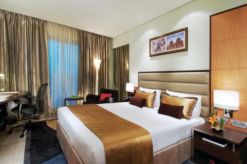 海得拉巴Vivanta Hyderabad, Begumpet的酒店客房设有一张大床和一张书桌。