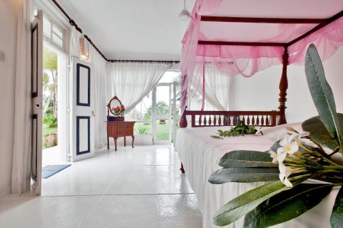 本托塔奇特拉阿育吠陀酒店的一间卧室配有一张粉红色天蓬床