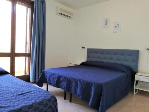 托雷拉皮罗Donna Carmela的一间卧室设有两张带蓝色床单的床和窗户。