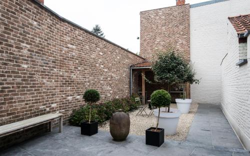 波佩林赫Maison de la Paix的种有盆栽植物的庭院和砖砌建筑
