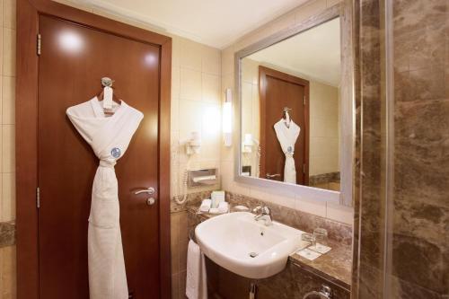 阿布扎比阿尔拉达阿亚罗塔纳阿布扎比酒店的浴室设有水槽,门上挂着白色连衣裙