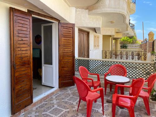 西迪基里尔Seaside Two-Bedroom Chalet Sidi Krir的阳台的天井配有红色椅子和桌子