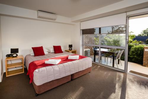 纽卡斯尔查尔斯敦公寓的一间卧室配有一张带红色枕头的床和一个阳台