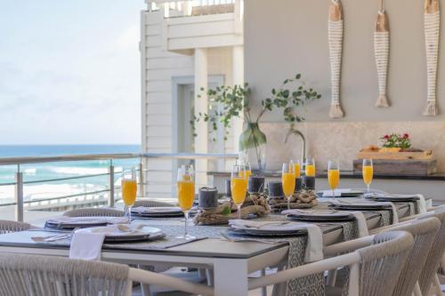 赫罗德斯湾Waves of Grace Seafront Villa的餐桌、椅子和橙汁杯