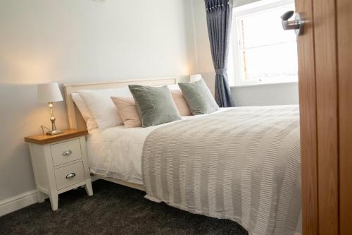 阿什伯恩Manifold Dale的卧室配有带枕头的床铺和窗户。