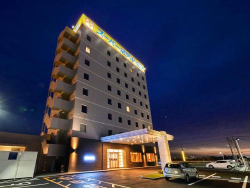 神栖市Super Hotel Kashima的停车场内有车辆的旅馆