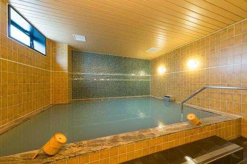 京都Sanco Inn Kyoto Hachijoguchi Shikinoyu的黄色瓷砖浴室内的大型游泳池